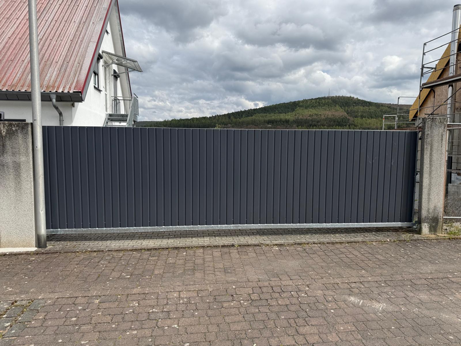 Schiebetor mit vertikalen Lamellen zwischen Betonpfeilern – Hauptbild